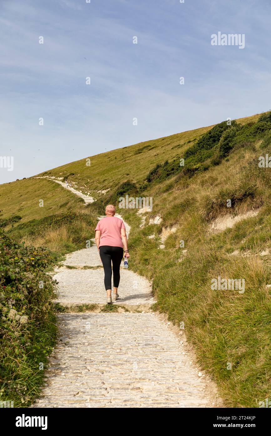 Modèle libéré femme dame marchant de Lulworth Cove à Durdle Door sur la côte jurassique du Dorset le long du chemin côtier sud-ouest, Angleterre, Royaume-Uni Banque D'Images