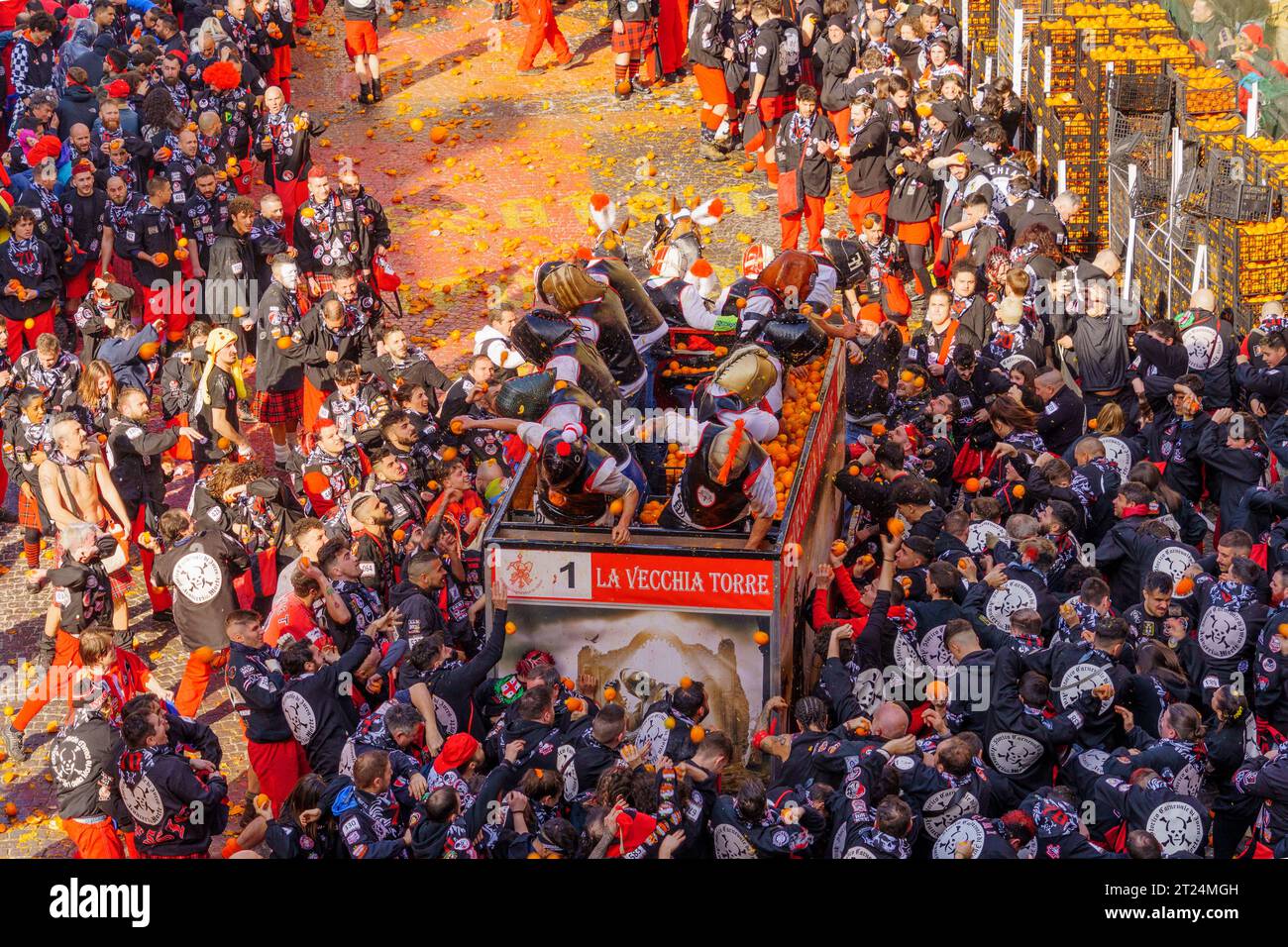 Ivrea, Italie - 19 février 2023: Des groupes de pansements traditionnels, et de la foule avec des chapeaux rouges, prennent part à la bataille des oranges, une partie de l'histor Banque D'Images