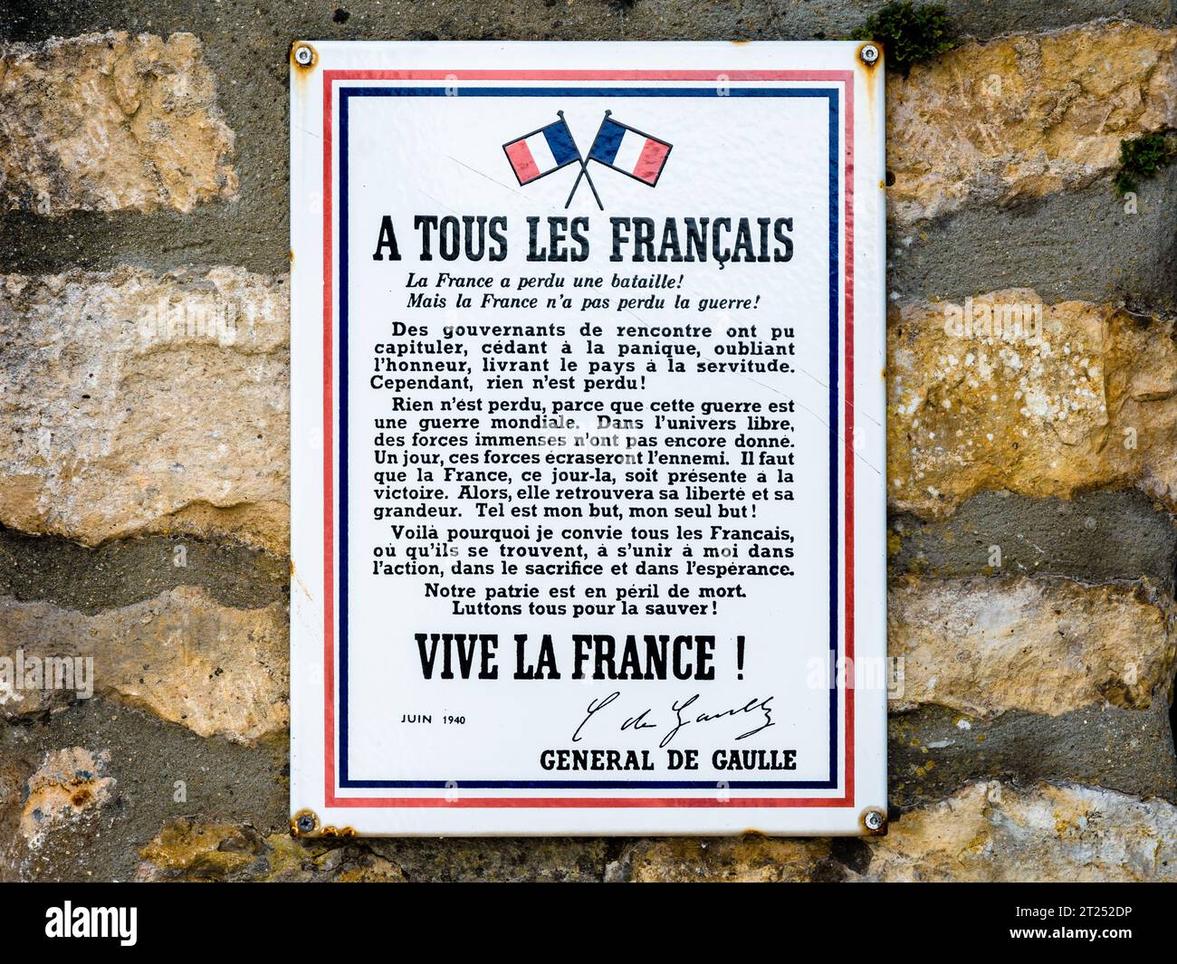 Gros plan d'une enseigne émaillée montrant l'affiche 'A tous les Français' du général de Gaulle, suite à l'appel du 18 juin 1940, sur un mur de pierre. Banque D'Images