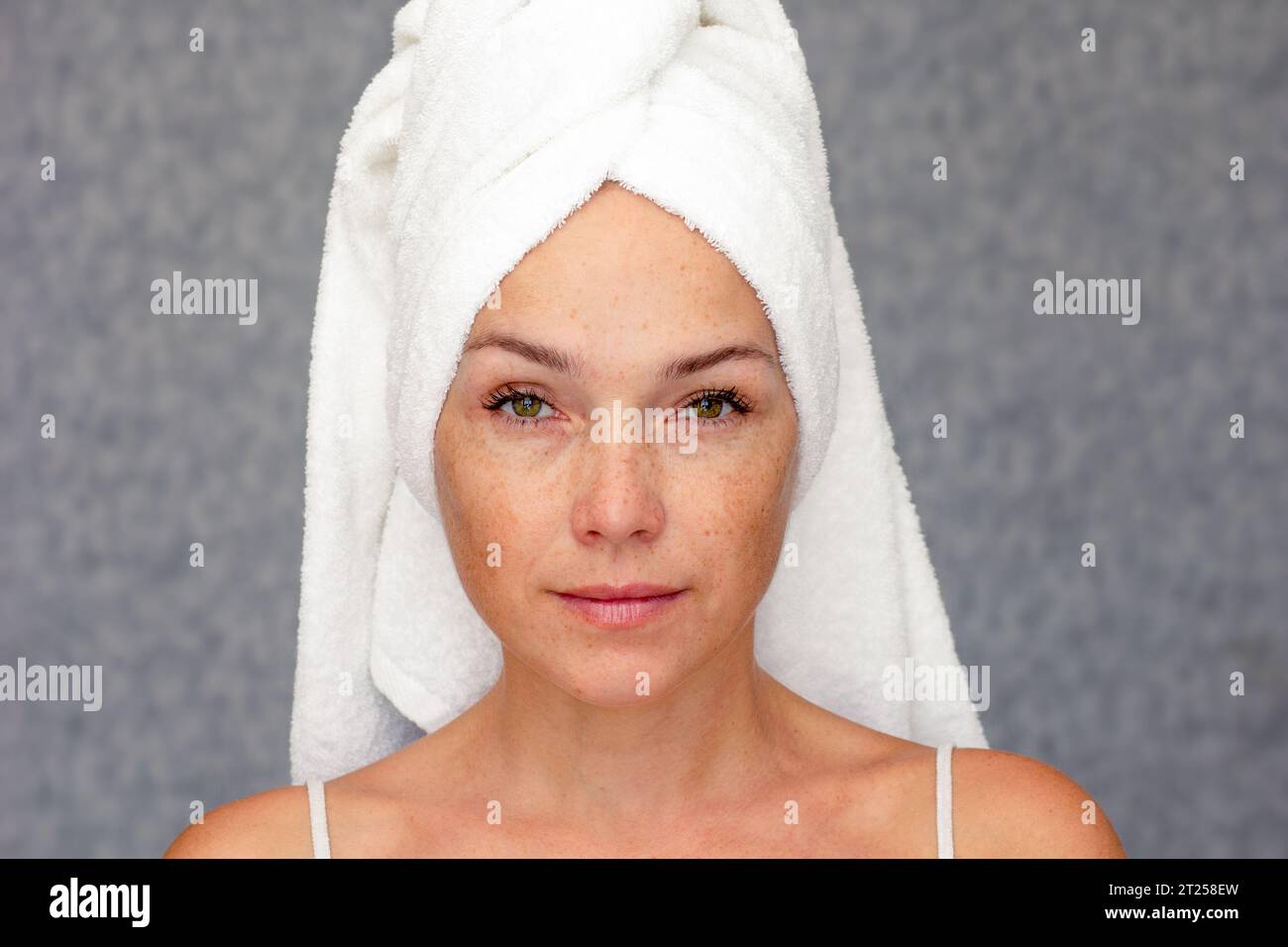 Portrait d'une femme caucasienne d'âge moyen des années 40 avec une serviette sur la tête regardant la caméra Banque D'Images