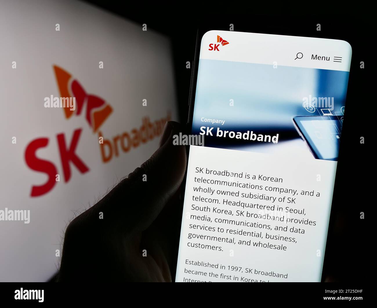 Personne détenant un téléphone cellulaire avec la page Web de la société coréenne de télécommunications SK Broadband Inc. Devant le logo. Concentrez-vous sur le centre de l'écran du téléphone. Banque D'Images