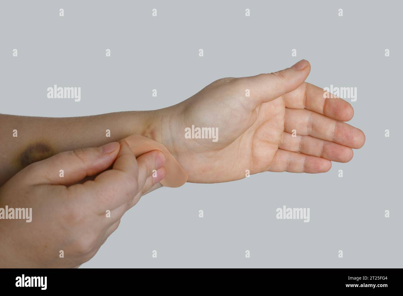 Main de femme avec un aide-bande sur fond blanc Banque D'Images