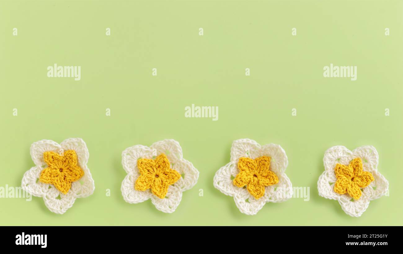 Motif de rangée de fleurs crochetées jaunes sur un fond vert Banque D'Images
