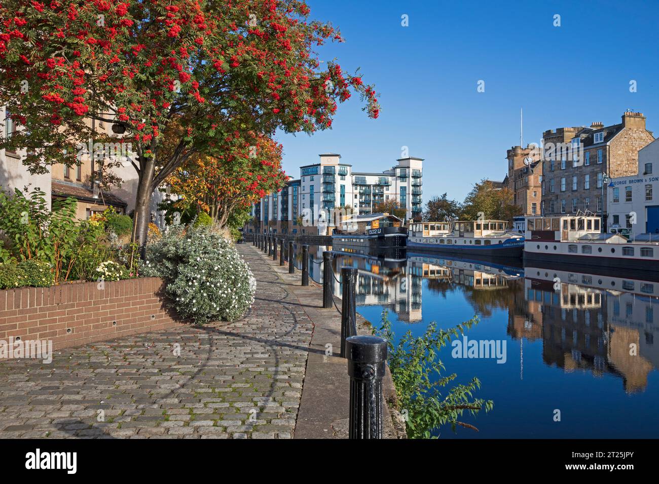 The Shore, avec Water of Leith Walkway sur la gauche, Leith, Édimbourg, Écosse, Royaume-Uni. 17 octobre 2023. Soleil sur Leith avec des eaux calmes reflétant les navires amarrés et les maisons résidentielles en arrière-plan. Banque D'Images