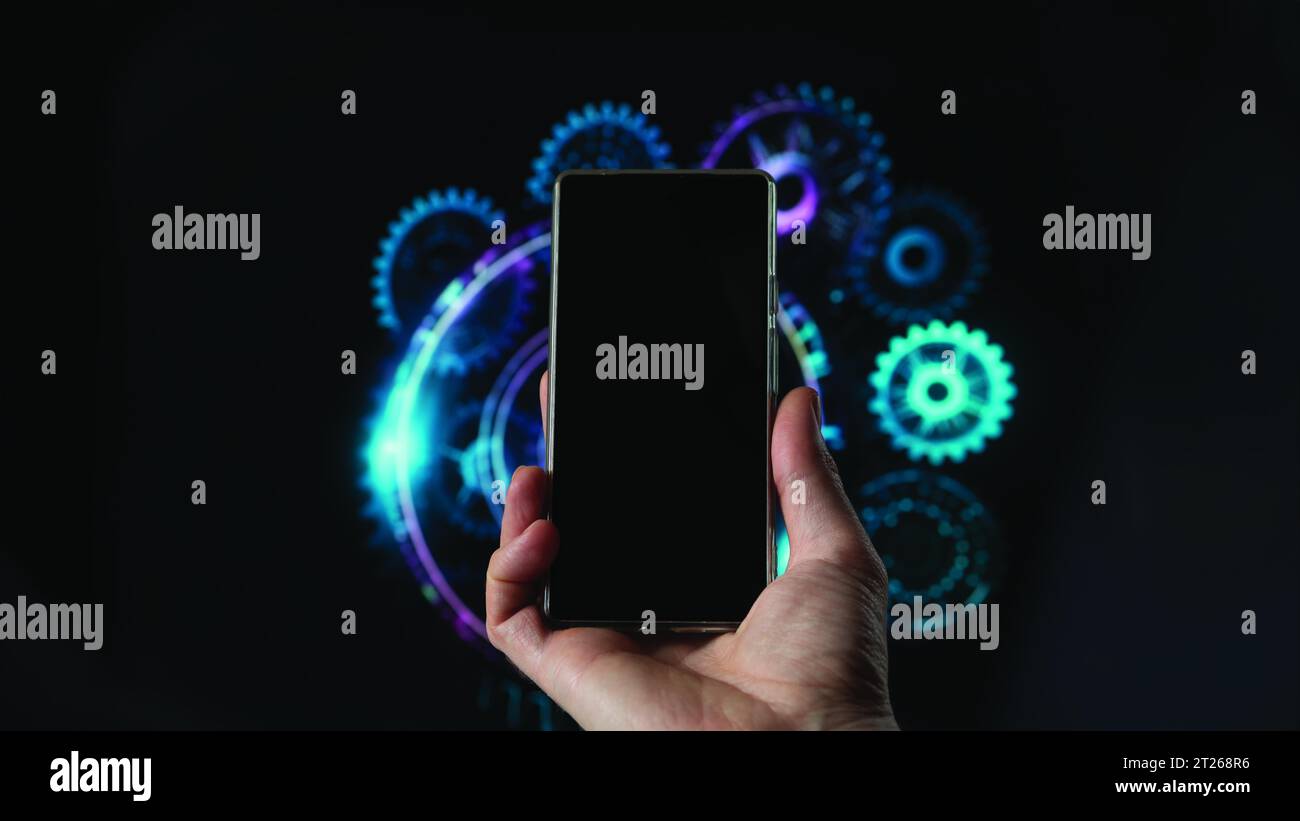 une main tient un écran noir de smartphone, fond un hologramme de machine. Banque D'Images