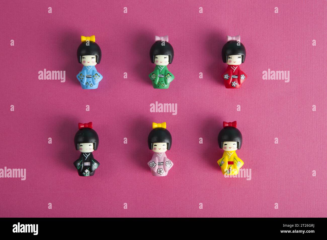 une collection de 6 poupées kokeshi en bois alignées en rangées et colonnes sur fond fushia. Photographies de natures mortes minimalistes et tendance. Banque D'Images