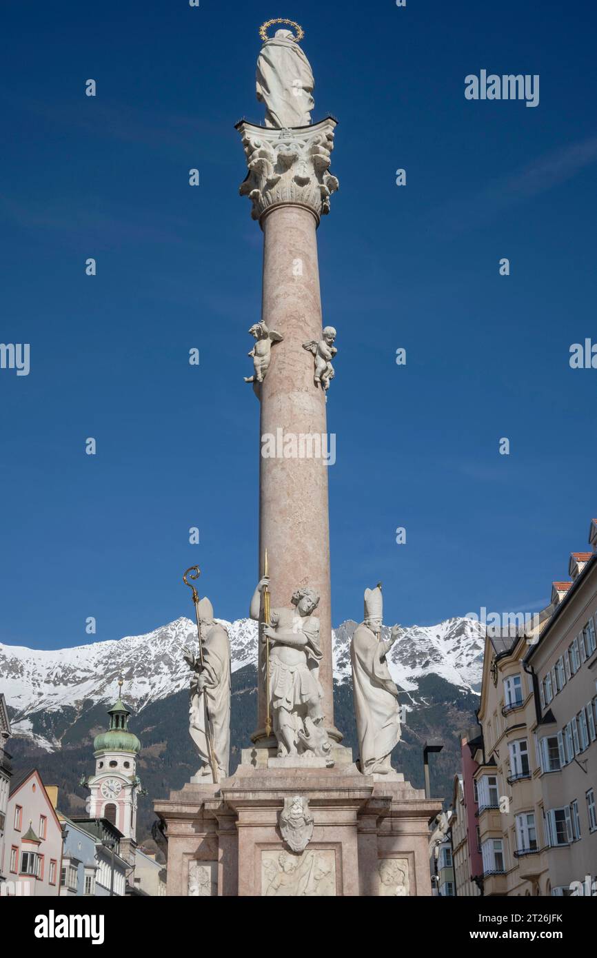 Autriche, Tyrol, Innsbruck, Annasaule ou colonne Sainte Anne sur Maria Theresien strase datant de 1706 avec des montagnes enneigées en arrière-plan. Banque D'Images
