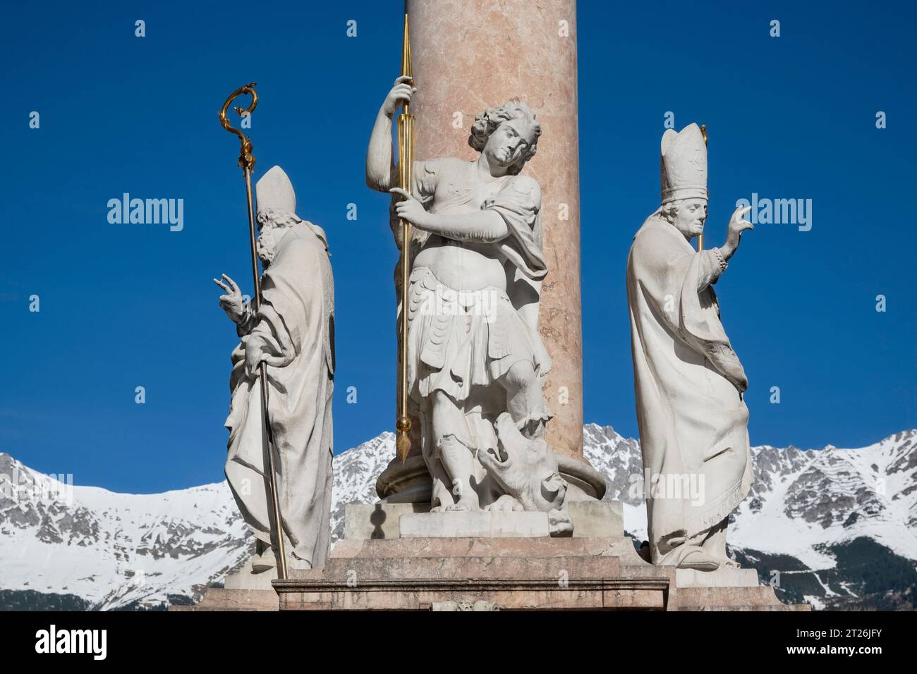 Autriche, Tyrol, Innsbruck, Annasaule ou colonne Sainte Anne sur Maria Theresien strase datant de 1706, détail montrant de gauche St Cassien, St George et St Vigilius avec des montagnes enneigées en arrière-plan. Banque D'Images
