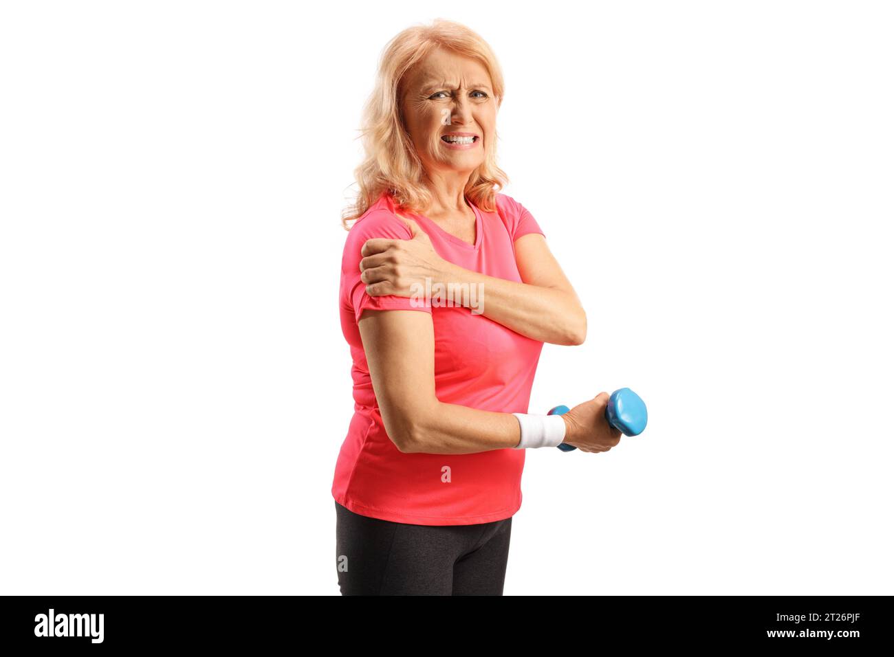 Femme mature en sportswear avec épaule douloureuse tenant un haltère et regardant la caméra isolée sur fond blanc Banque D'Images