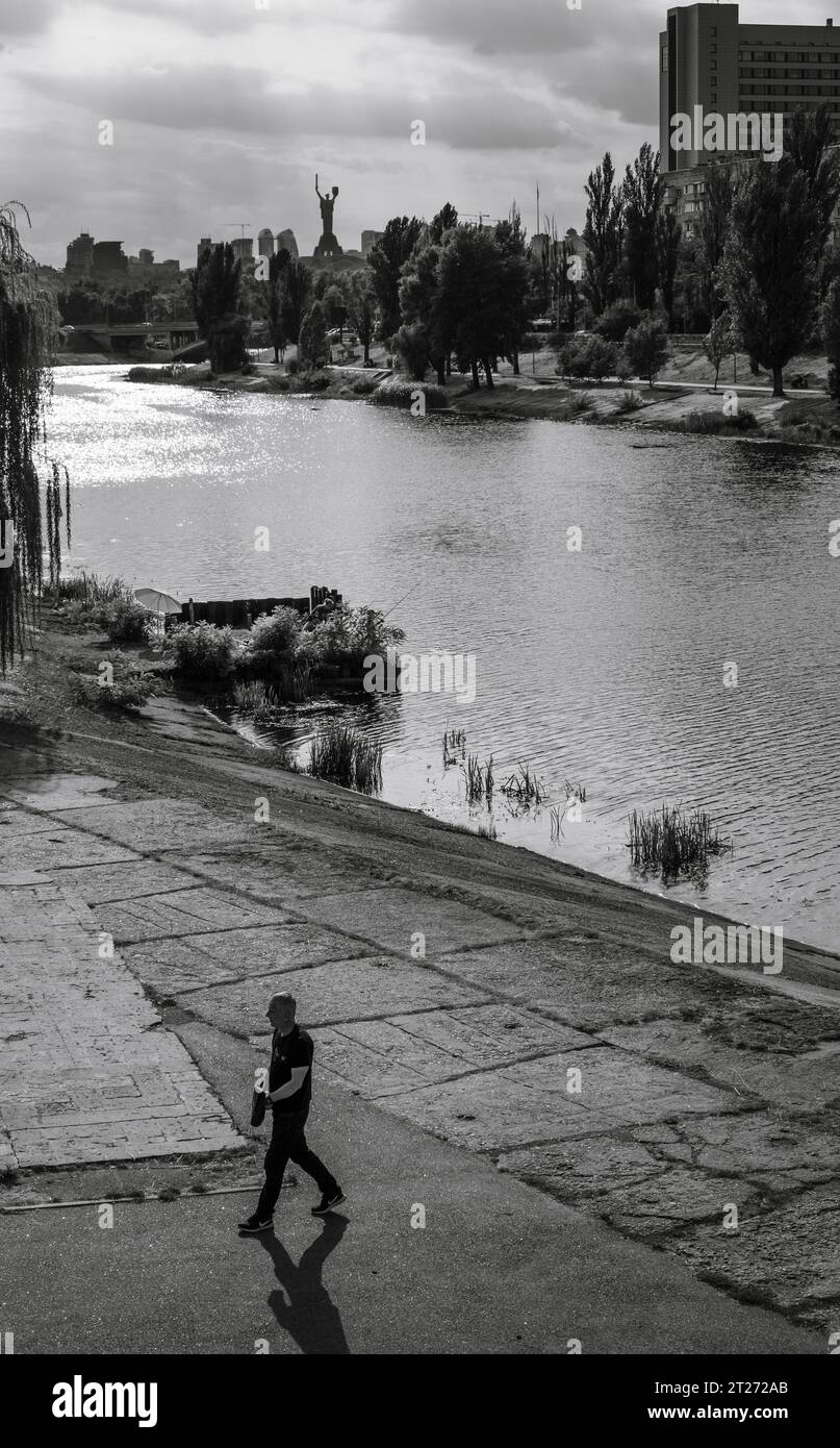 Un homme marchant devant le canal du Dniepr dans le parc public Rusanivka à Kiev, en Ukraine Banque D'Images