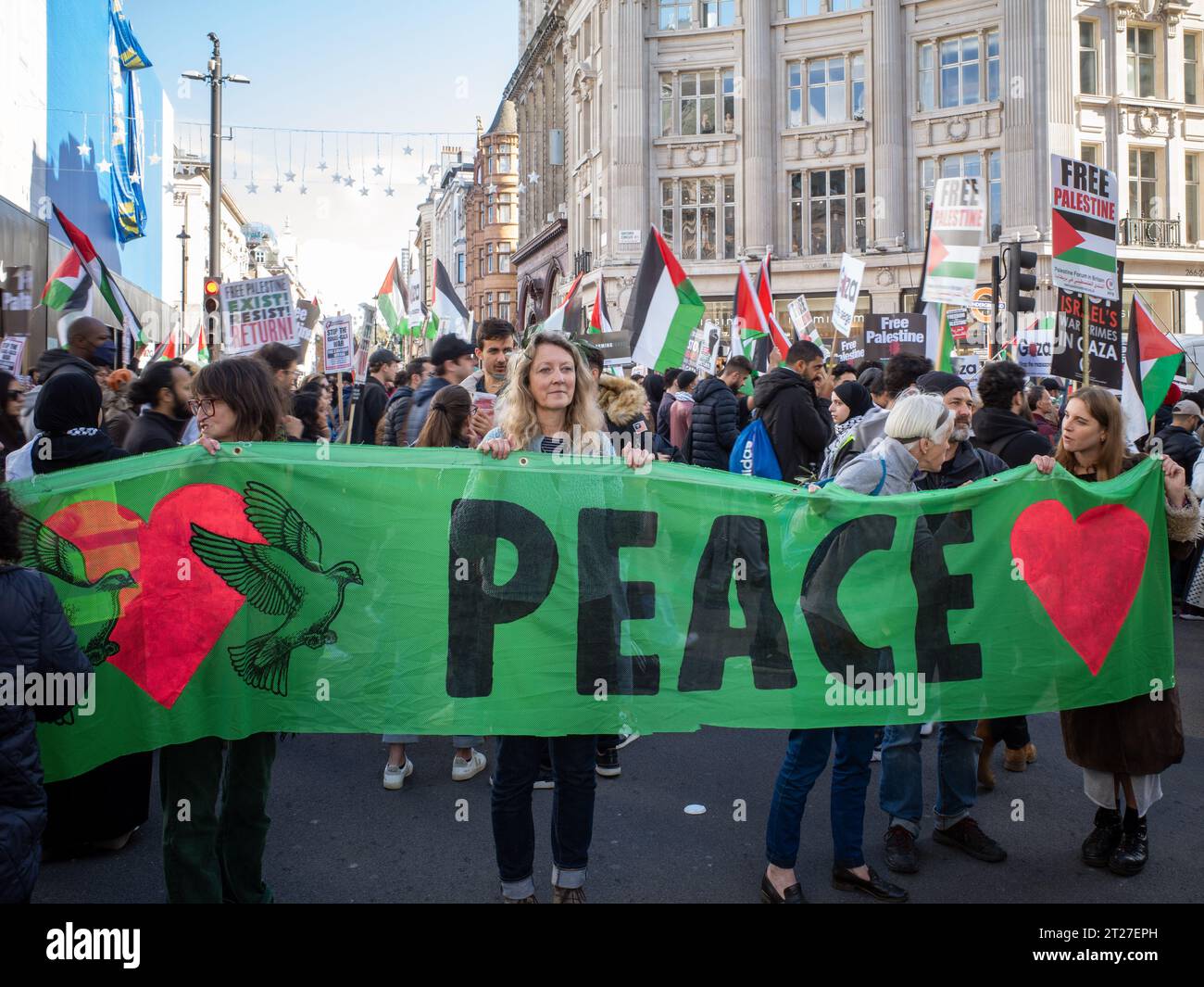 Une femme tient une grande bannière verte de « paix » à Oxford Circus, dans le centre de Londres, pendant la marche / manifestation Pro Palestine le 14 octobre 2023. Banque D'Images