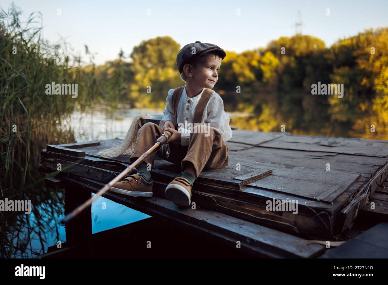 Un petit garçon pêche au coucher du soleil sur le lac Banque D'Images