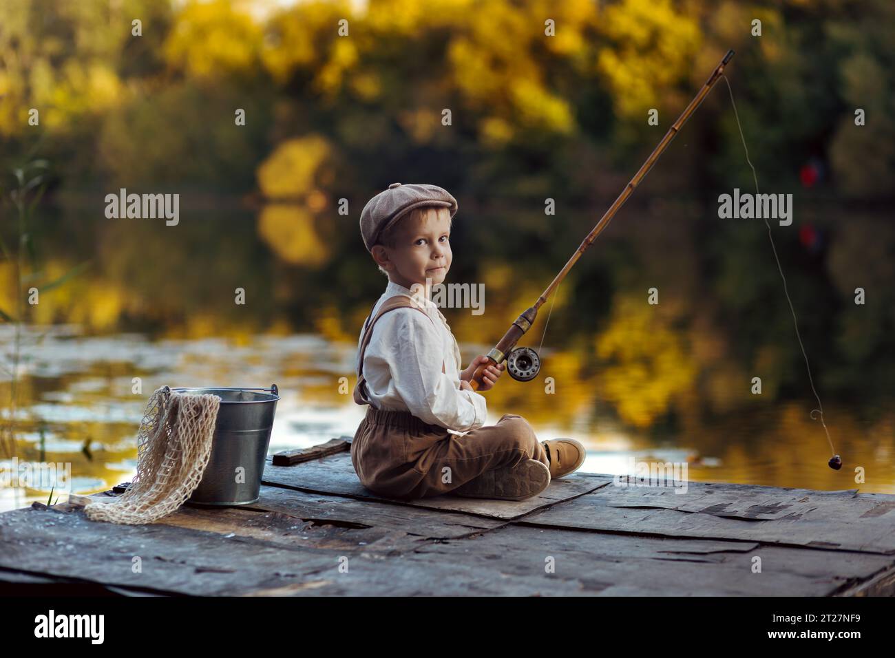 Un petit garçon pêche au coucher du soleil sur le lac Banque D'Images