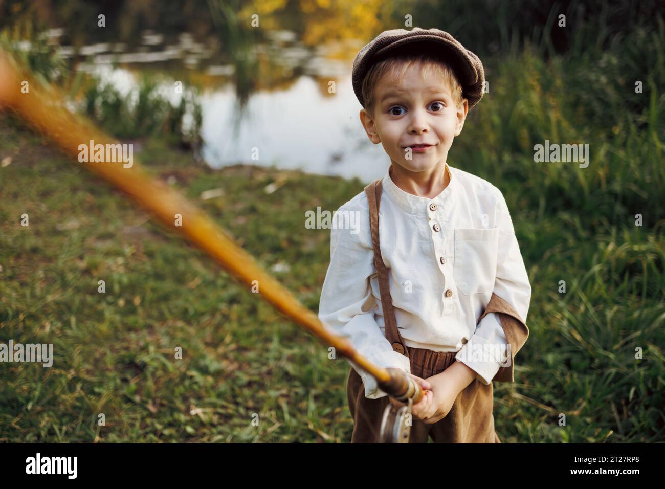 Enfant avec canne à pêche. Pêche enfant au lac d'automne Banque D'Images