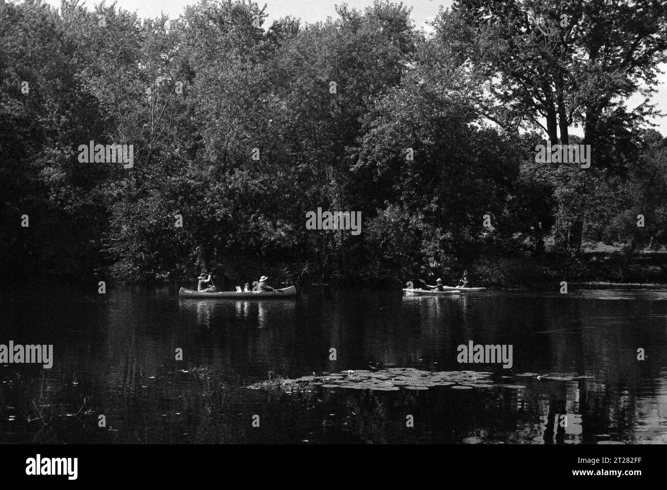 Les touristes font du bateau dans des canoës et des kayaks sur la rivière Concord par une journée ensoleillée d'été. L'image a été capturée sur film analogique noir et blanc. Banque D'Images