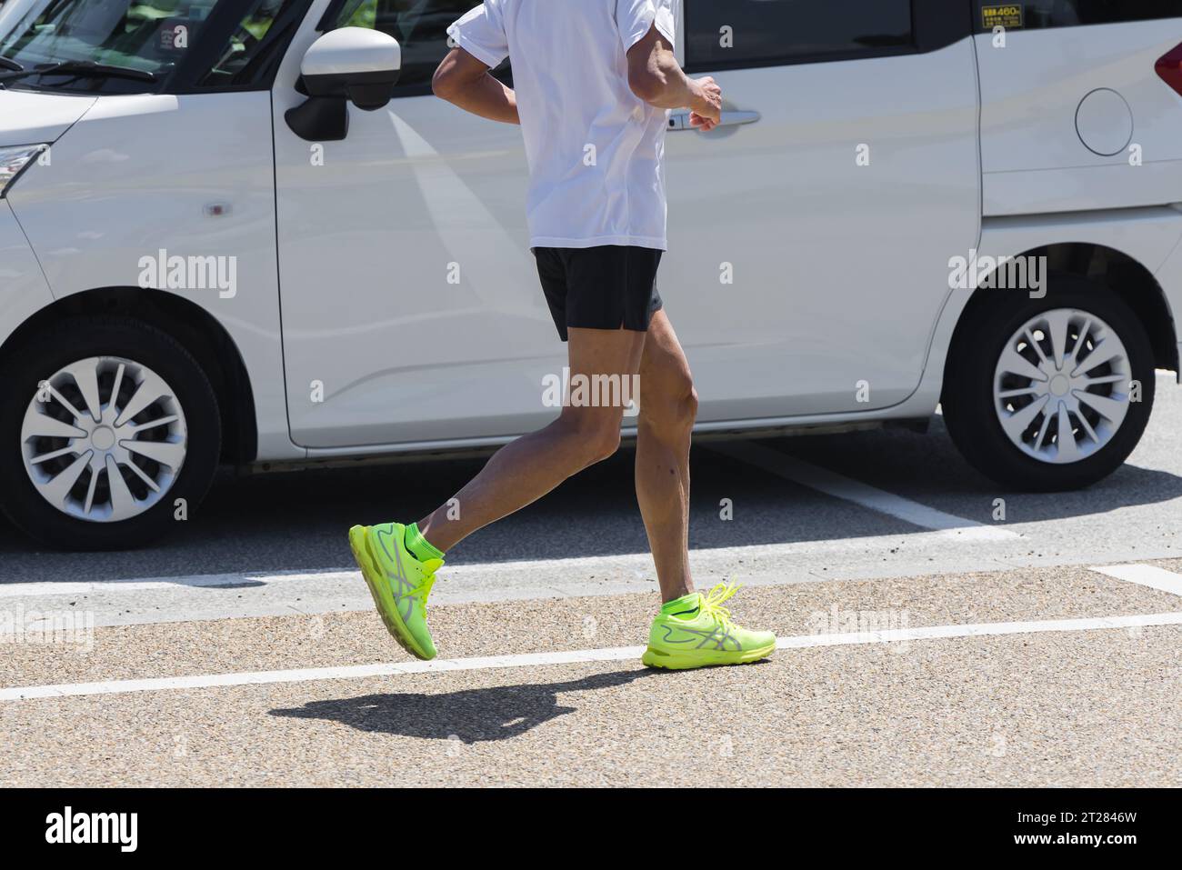 photo d'un homme faisant du jogging dans une rue de la ville avec une camionnette derrière lui Banque D'Images