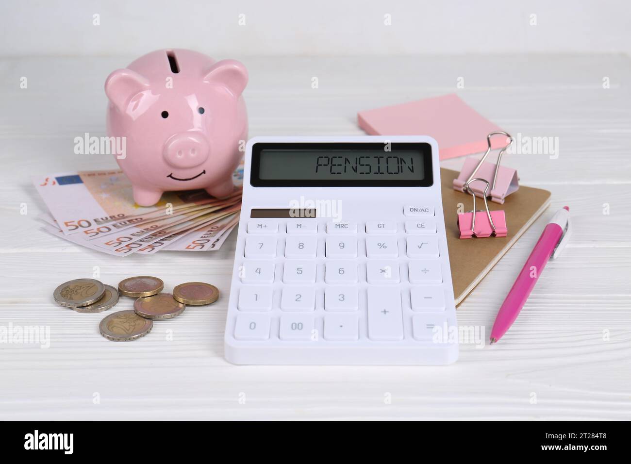 Calculatrice, tirelire, argent, cahier et stylo sur table en bois blanc. Concept de retraite Banque D'Images