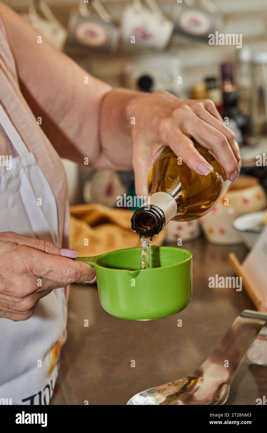 Le chef verse du vin blanc dans une tasse à mesurer Banque D'Images