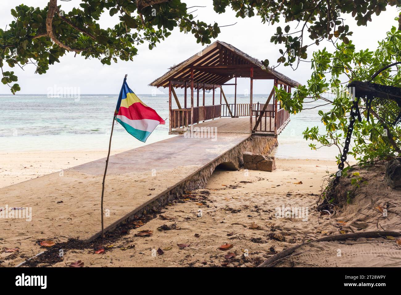 Plage d'Anse Union, île de la Digue, Seychelles. Paysage avec drapeau et un gazebo vide à la vieille jetée sur un fond Banque D'Images
