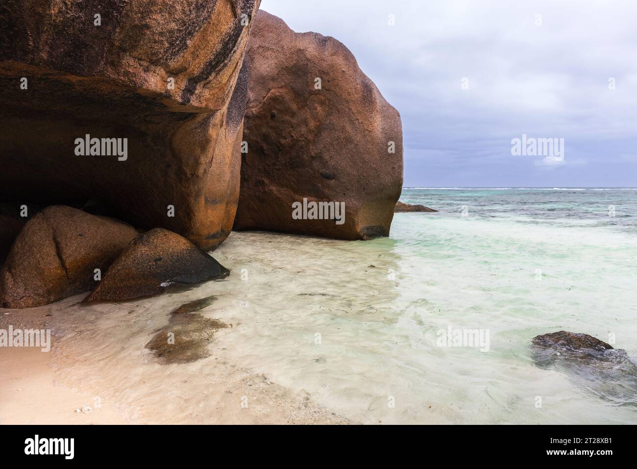 Roches sombres sur la côte de l'île de la Digue, Seychelles. Vue sur la plage d'Anse Union Banque D'Images