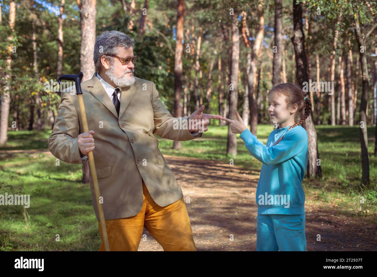 Grand-père marche avec sa petite-fille dans le parc. Un grand-père drôle et une petite fille jouent et plaisantent. Banque D'Images