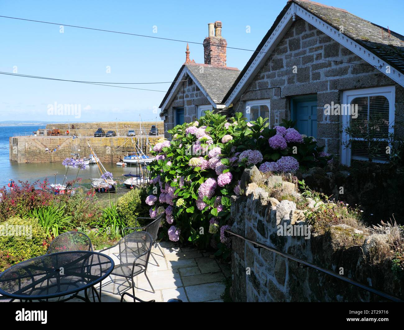 Maison avec des plantes de jardin colorées en face du port de bateau Mousehole en Cornouailles en Angleterre Banque D'Images