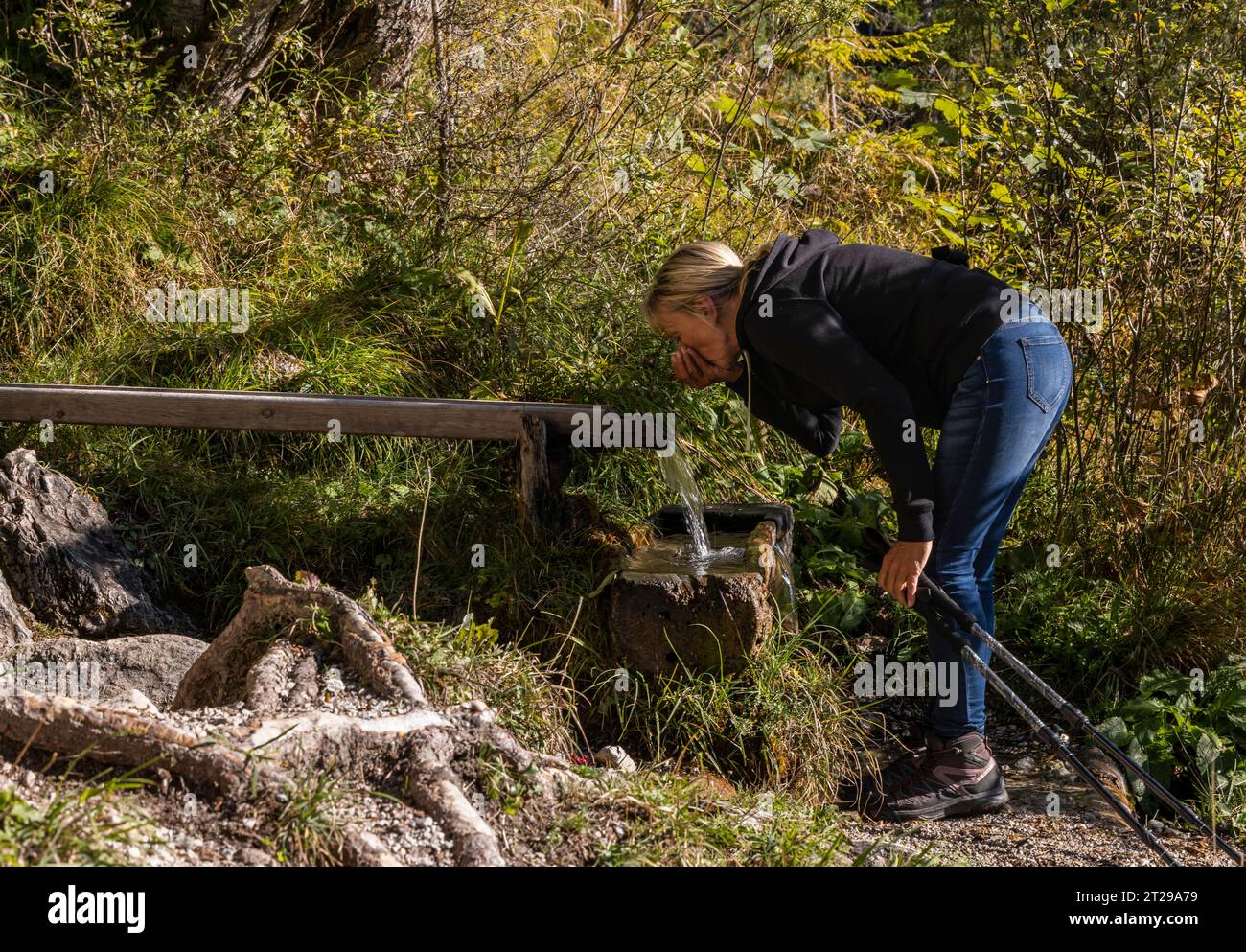 Randonneur se rafraîchit à la fontaine en bois avec de l'eau de source à Maria Alm, Salzbourg Banque D'Images