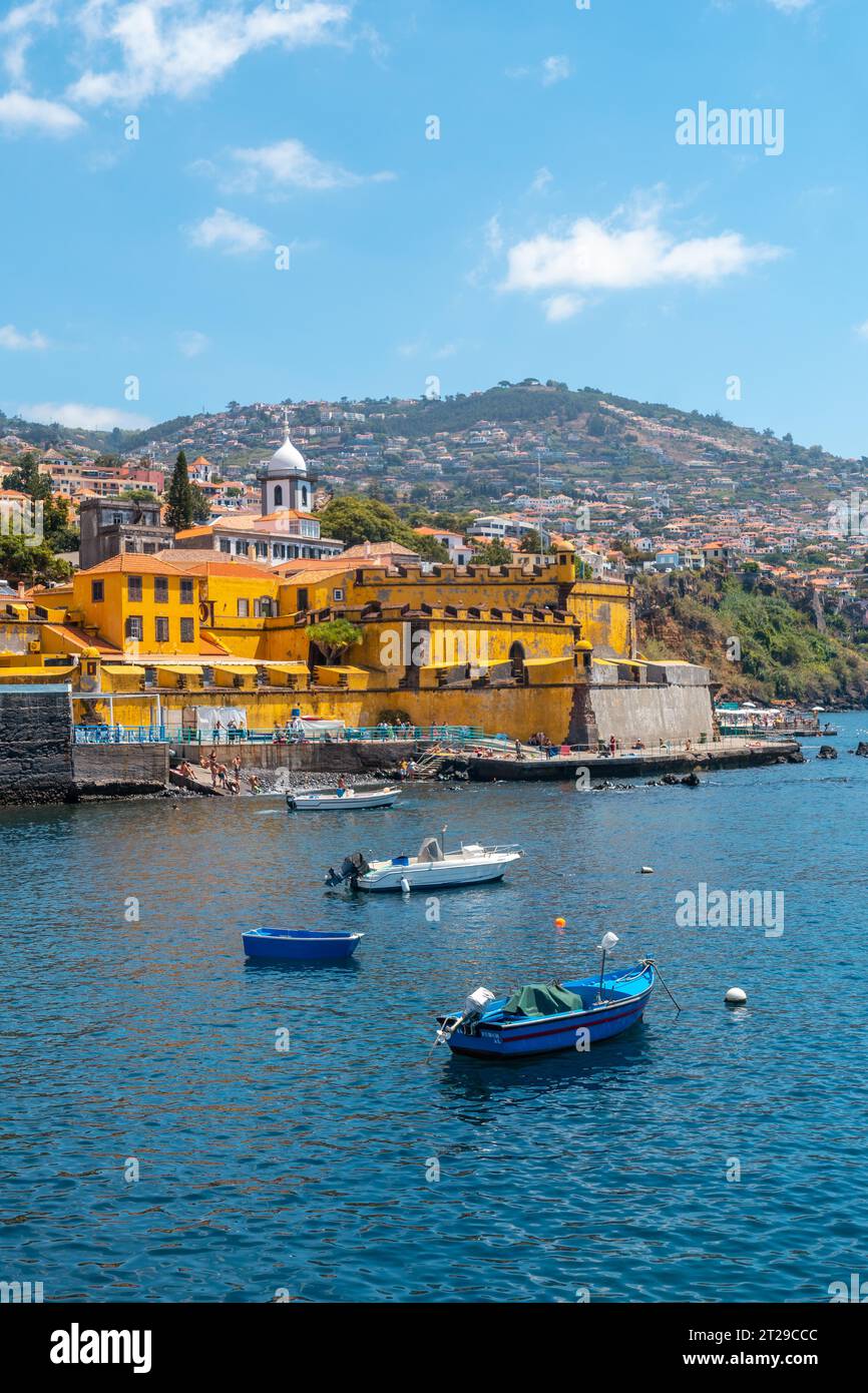 Petits bateaux de pêche à côté de la forte de Sao Tiago sur la plage de Funchal, en été au bord de la mer. Madère Banque D'Images