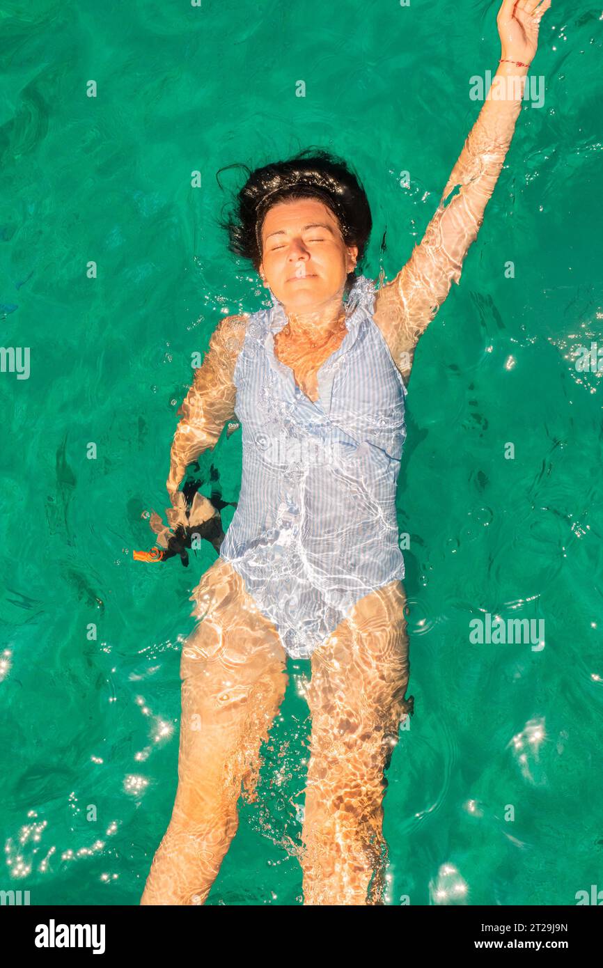 Femme portant un maillot de bain blanc bleu se relaxant dans la mer profitant de l'été dans l'île de Zakynthos en Grèce. Vue de dessus. Banque D'Images