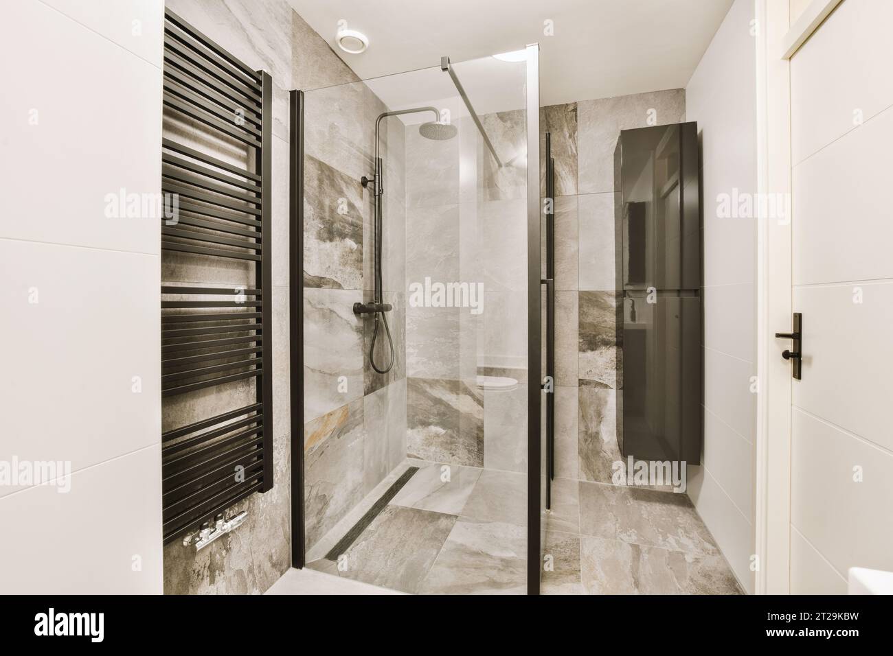 Intérieur de salle de bains élégante avec cabine de douche et murs en marbre et carreaux blancs dans la maison moderne Banque D'Images