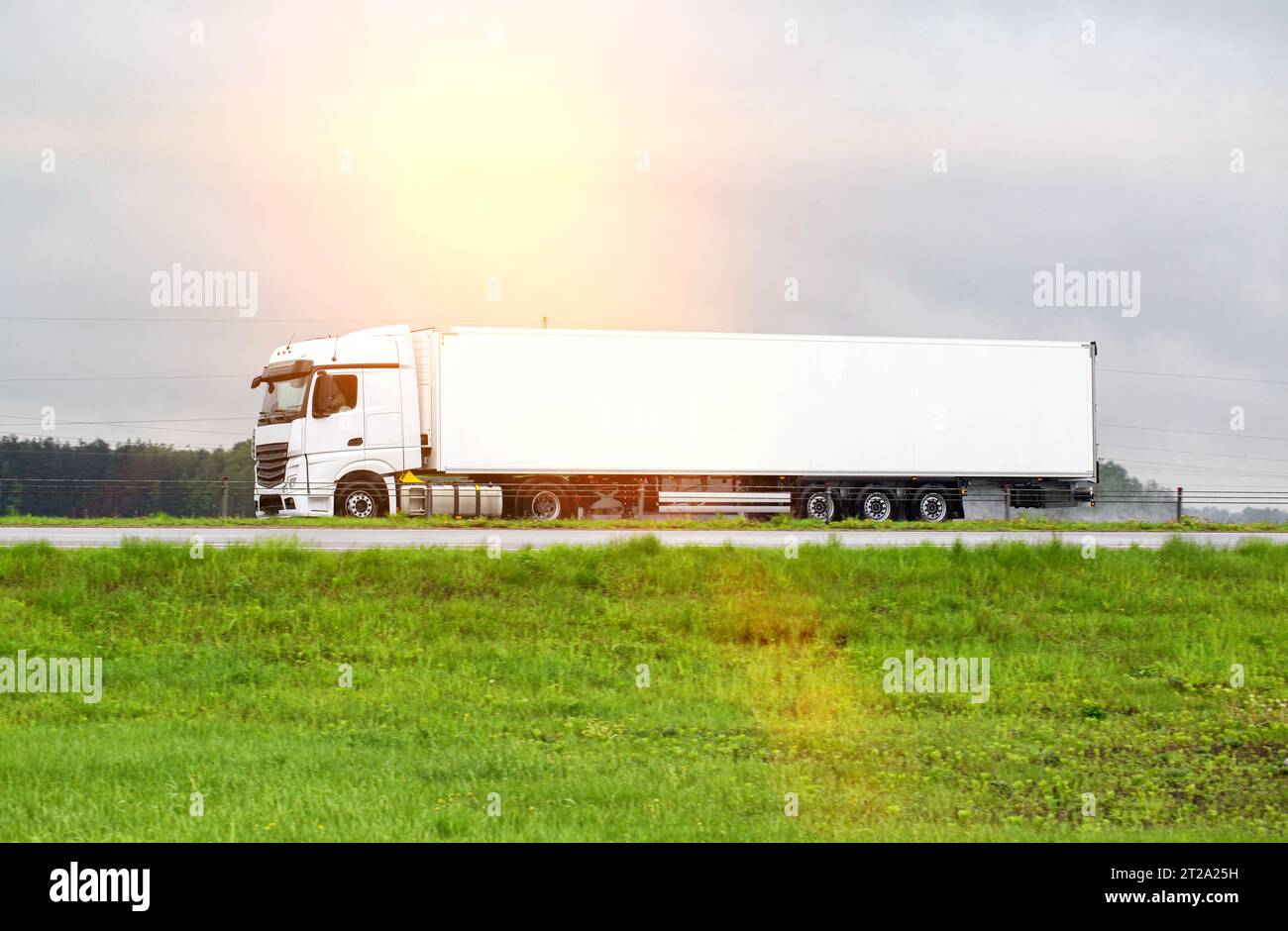 Un beau nouveau camion semi-remorque blanc transporte des marchandises le long de la route en été. Concept de transport commercial de marchandises, services logistiques. Tr Banque D'Images