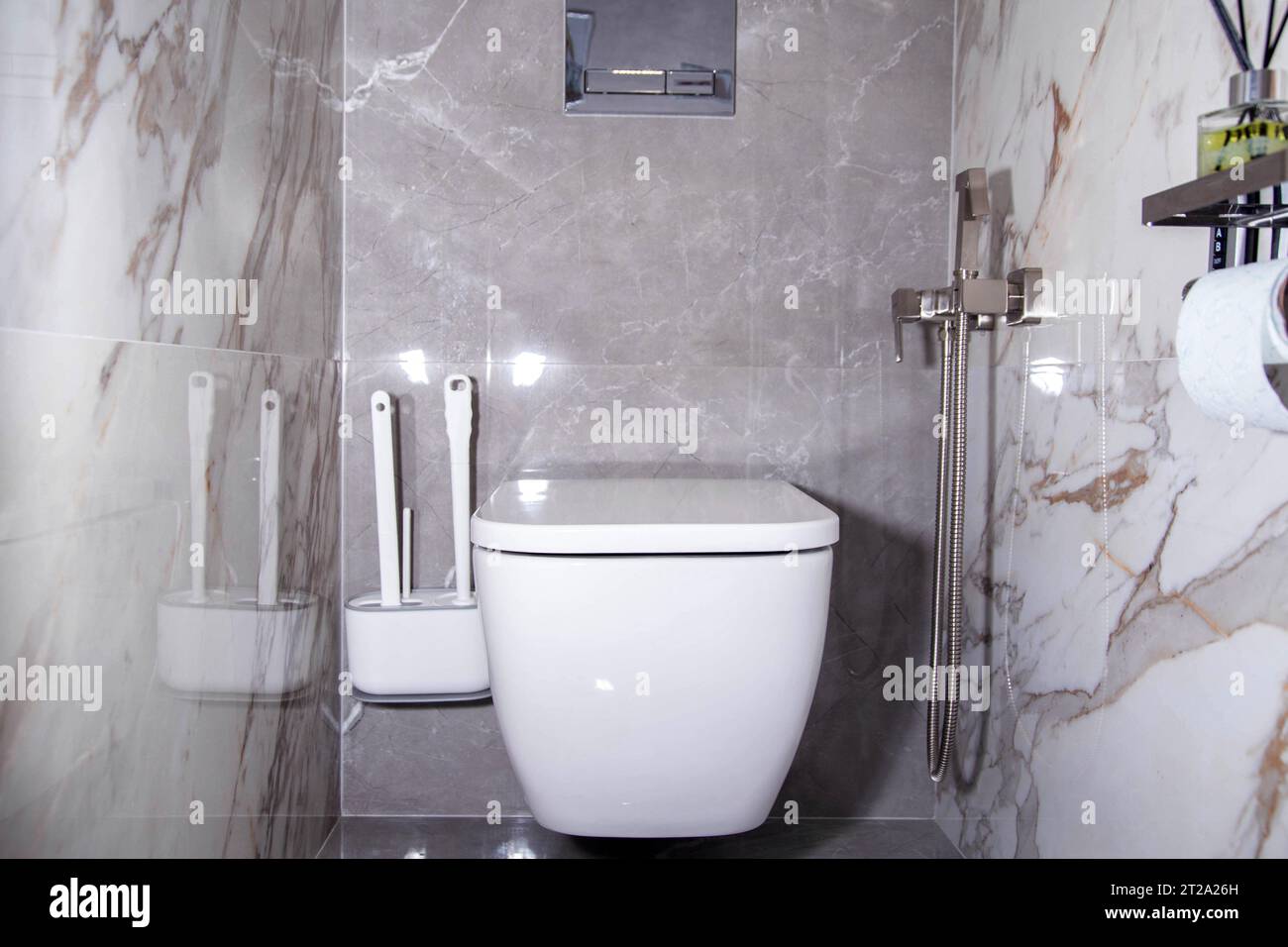 Salle de bain moderne avec toilettes suspendues au mur et carreaux de grès cérame gris. Douche hygiénique sur le mur Banque D'Images