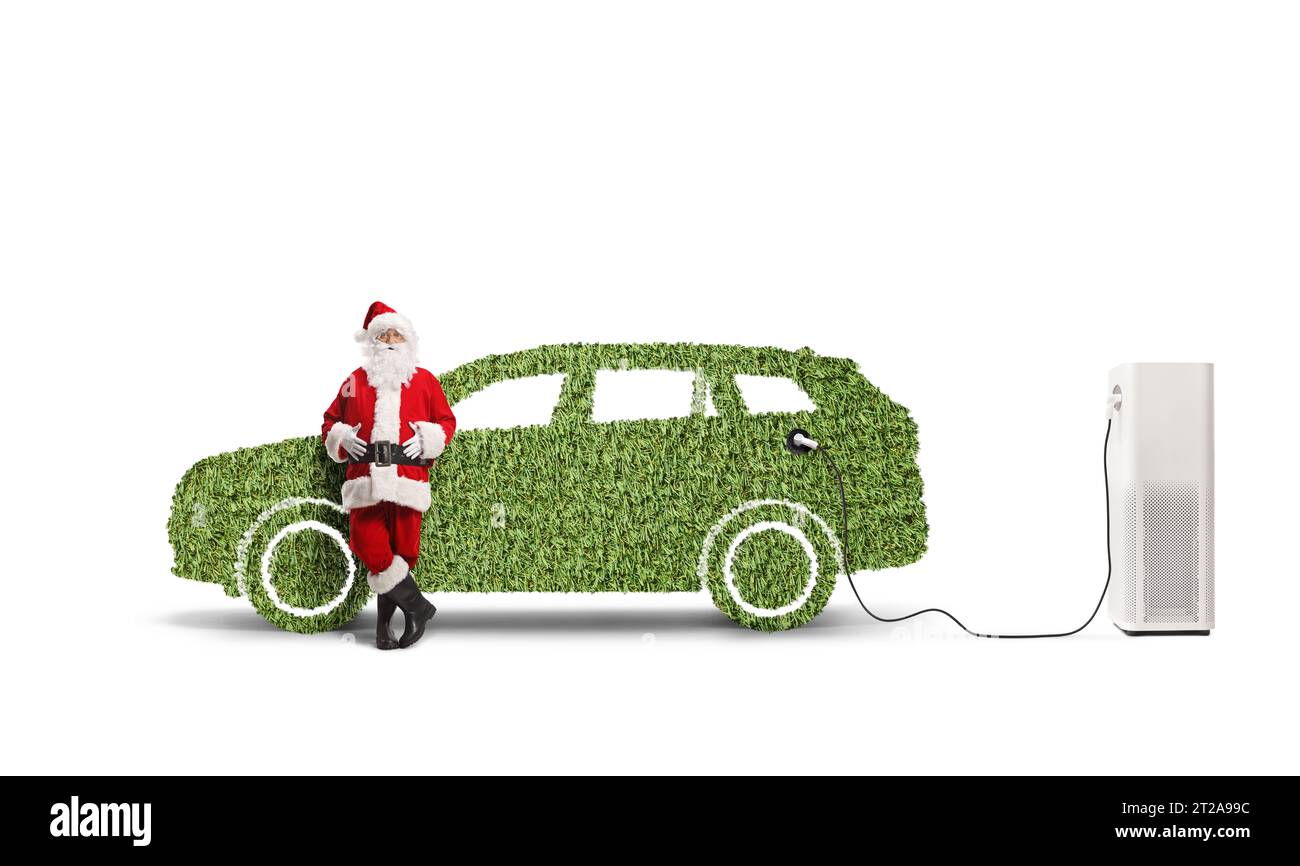 Père noël appuyé sur une voiture verte à une station de charge isolée sur fond blanc Banque D'Images