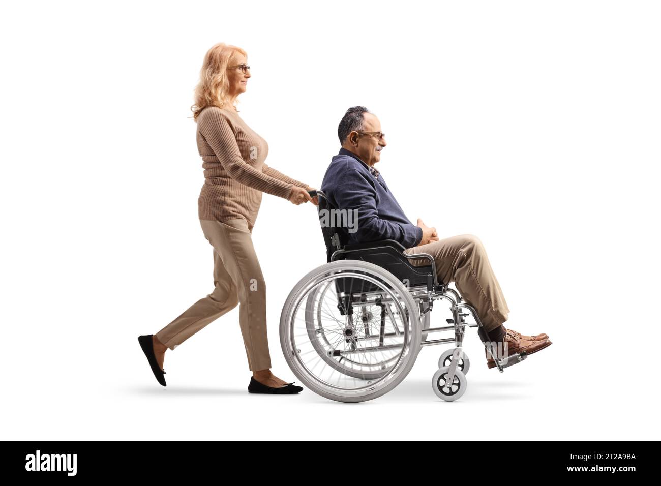Plan de profil en longueur d'une femme poussant un homme mature handicapé dans un fauteuil roulant isolé sur fond blanc Banque D'Images