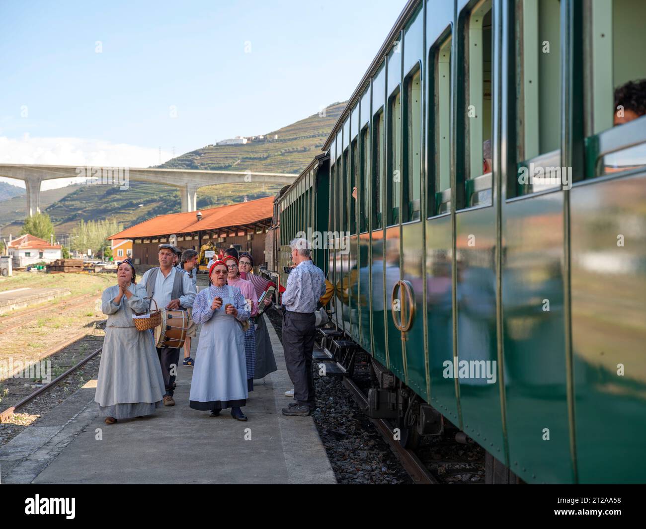 Les gens en vêtements traditionnels chantent à côté du train historique du Douro qui circule entre Régua et Tua en suivant le fleuve Douro, Portugal, Europe Banque D'Images