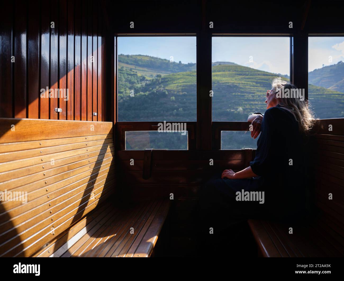 Femme qui monte le train historique du Douro seule tout en regardant par la fenêtre le paysage le long du fleuve Douro, Portugal Banque D'Images