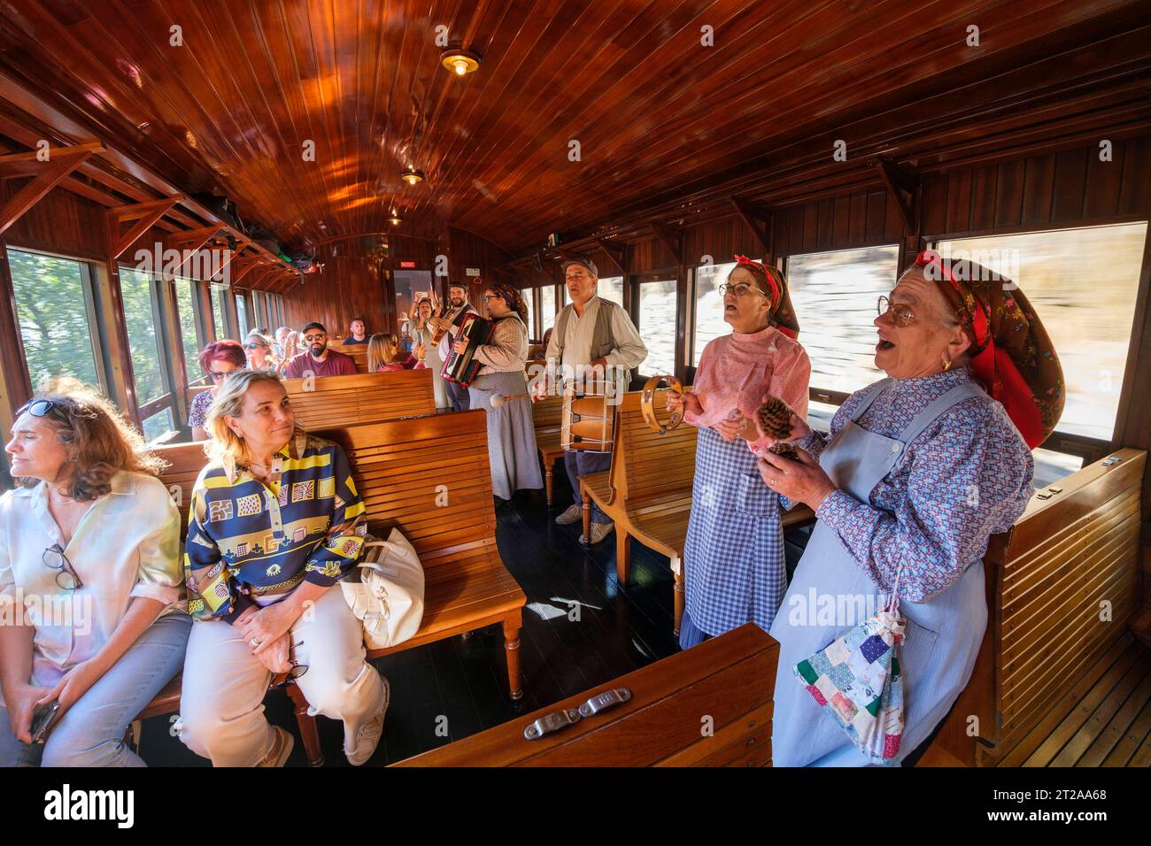 Les gens en vêtements traditionnels chantent à l'intérieur du train historique du Douro qui circule entre Régua et Tua en suivant le fleuve Douro, Portugal, Europe Banque D'Images