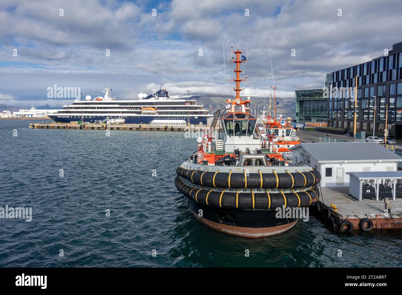 Atlas Ocean Voyages World Traveller petit bateau de croisière de style yacht à Port Reykjavik Islande avec des Tugboats à l'extérieur du Harpa Centre Banque D'Images