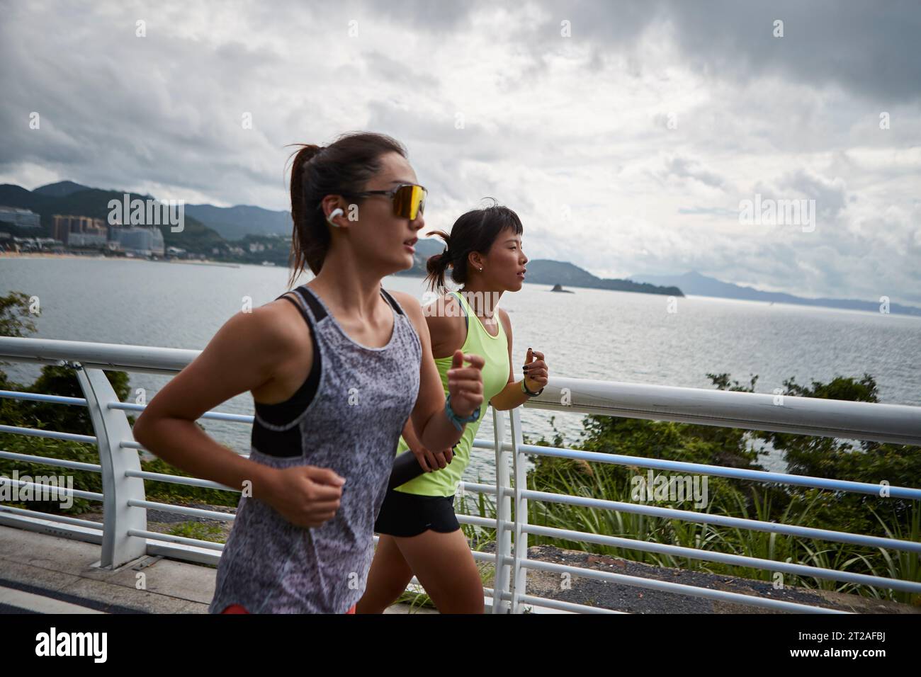 deux jeunes femmes asiatiques joggeurs féminins courant à l'extérieur dans le parc au bord de la mer Banque D'Images