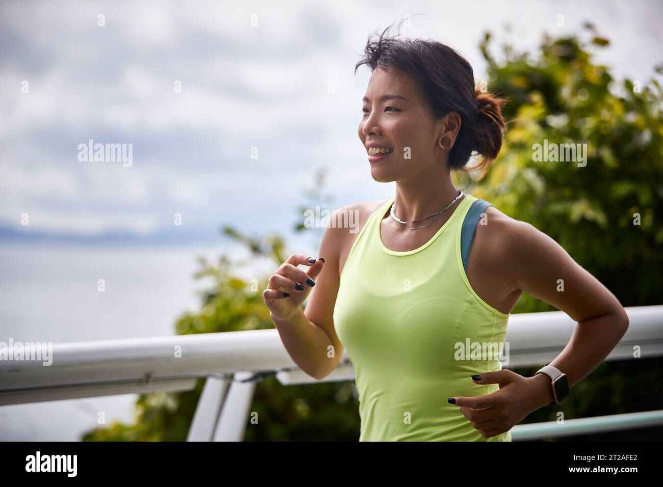 jeune femme asiatique athlète féminine courant en plein air dans le parc au bord de la mer Banque D'Images