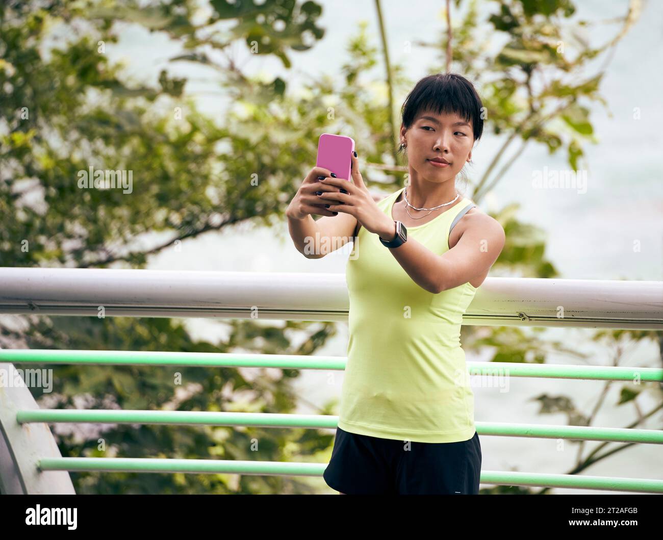 jeune femme asiatique prenant un selfie à l'extérieur en utilisant un téléphone portable Banque D'Images