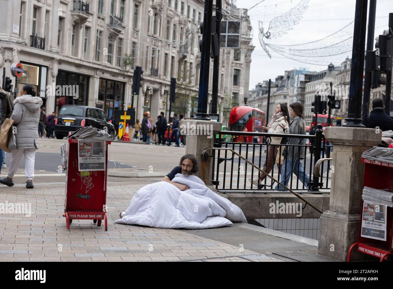 Homme sans abri, essayant de se réchauffer devant la station de métro Oxford Circus avec une couette tout en dormant dans les rues de Londres, Angleterre, Royaume-Uni Banque D'Images