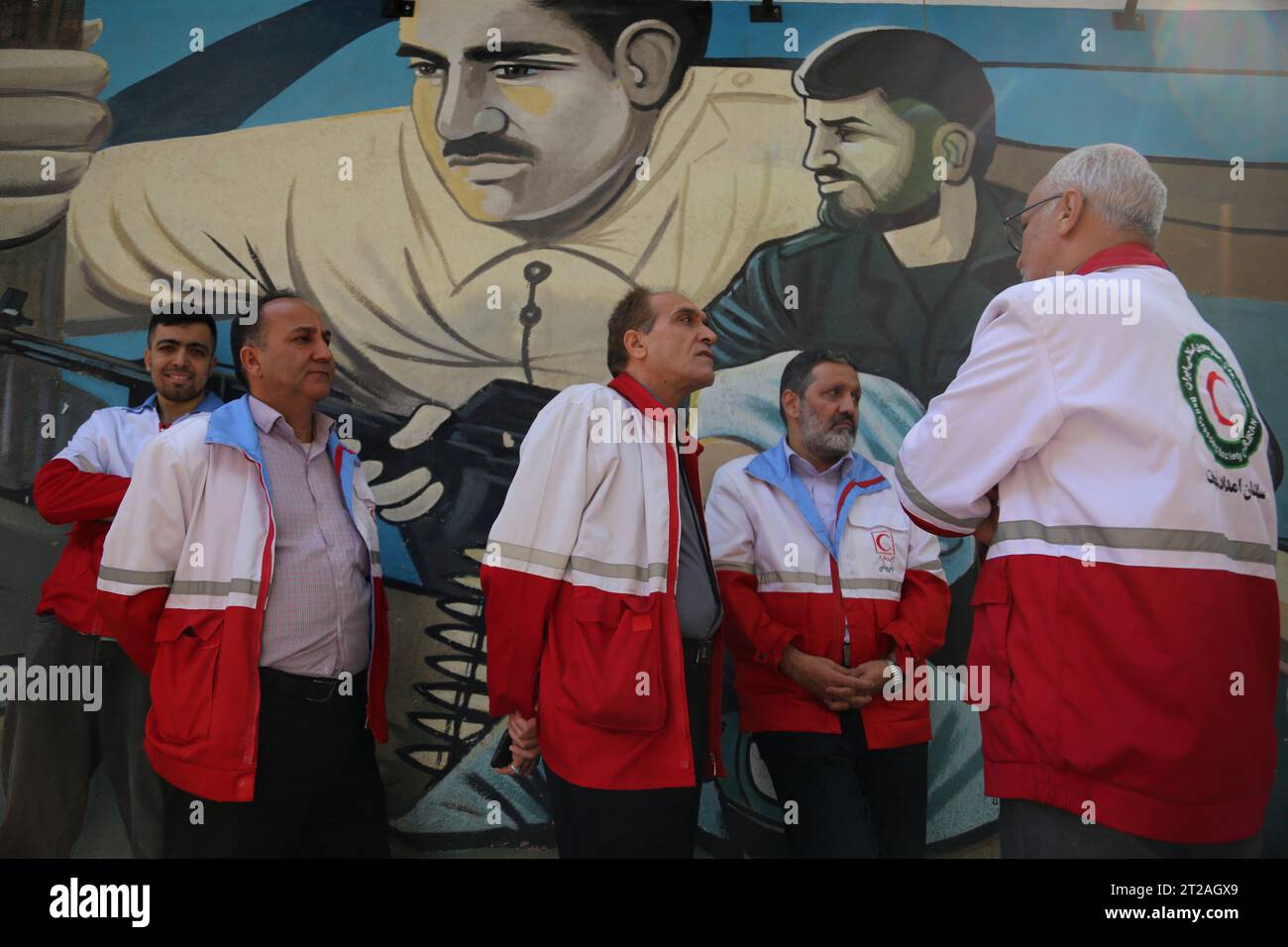 Téhéran, Iran. 18 octobre 2023. Des membres du Croissant-Rouge international se tiennent à côté d'une fresque lors d'une manifestation anti-israélienne sur la place Palestine dans le centre-ville de Téhéran. La manifestation a éclaté après que les autorités dirigées par le Hamas à Gaza ont déclaré que des centaines de personnes avaient été tuées dans une frappe israélienne contre un hôpital à Gaza le 17 octobre. Selon les Forces de défense israéliennes (FDI), le Jihad islamique est responsable de l’échec du tir de roquette qui a frappé l’hôpital. L'Iran, l'ennemi juré d'Israël, qui soutient à la fois le Hamas et les militants du Hezbollah basés au Liban, a mis en garde à plusieurs reprises contre une invasion de Gaza et a soulevé la question le Oct Banque D'Images