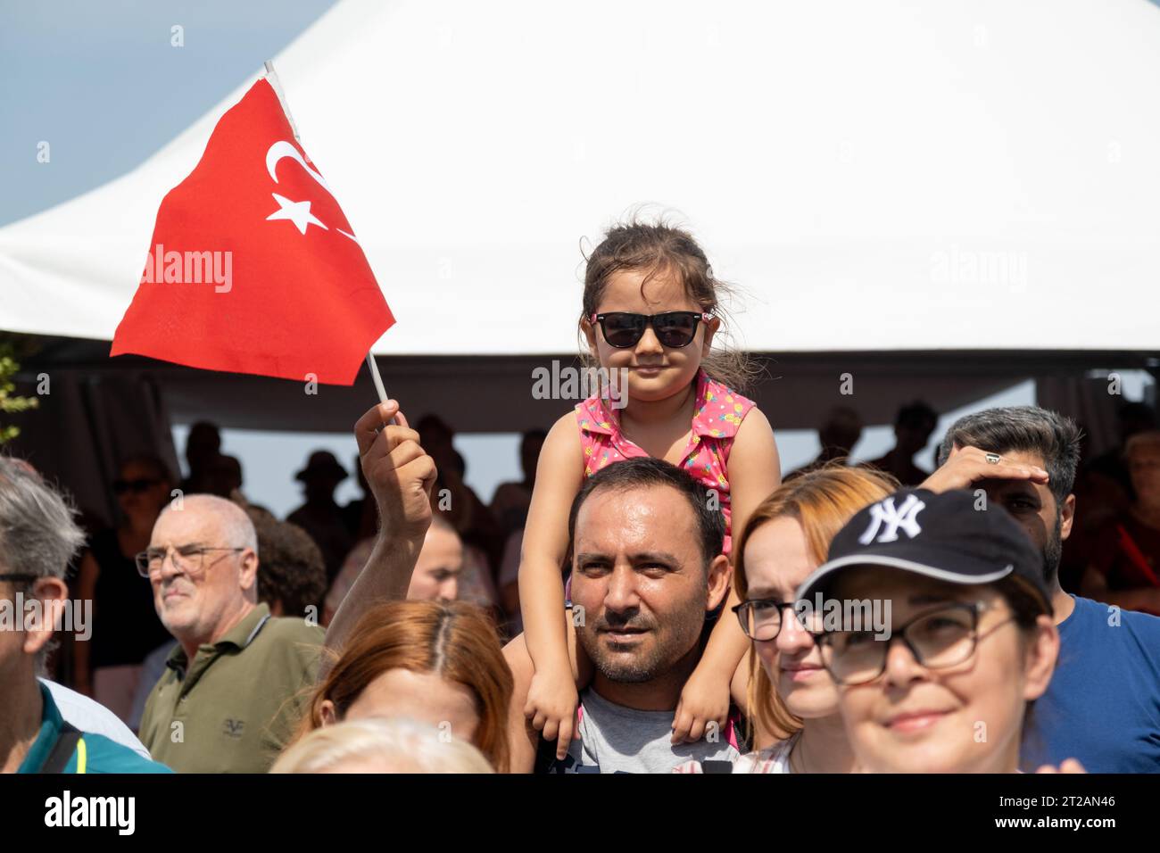Izmir, Turquie, le 9 septembre 2023 : un moment réconfortant capturant une fillette de 8 à 9 ans avec des lunettes de soleil, perchée sur les épaules de son père, agitant le Banque D'Images