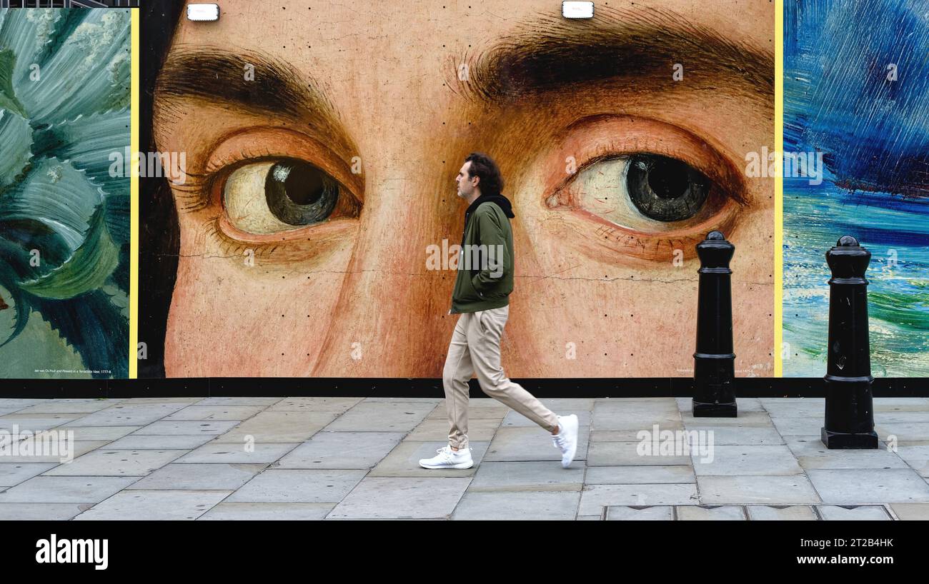Un homme marchant près d'une paire d'yeux d'un portrait peint par Antonello de Messina sur une affiche dans le centre de Londres Banque D'Images