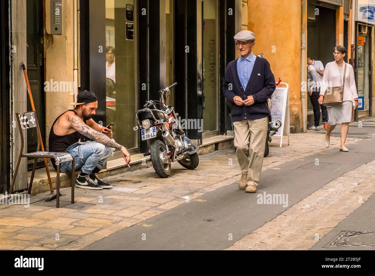 Personnes individuelles marchant ou assis sur le trottoir d'une rue pavée dans la vieille ville, Aix-en-Provence, sud de la France. Banque D'Images