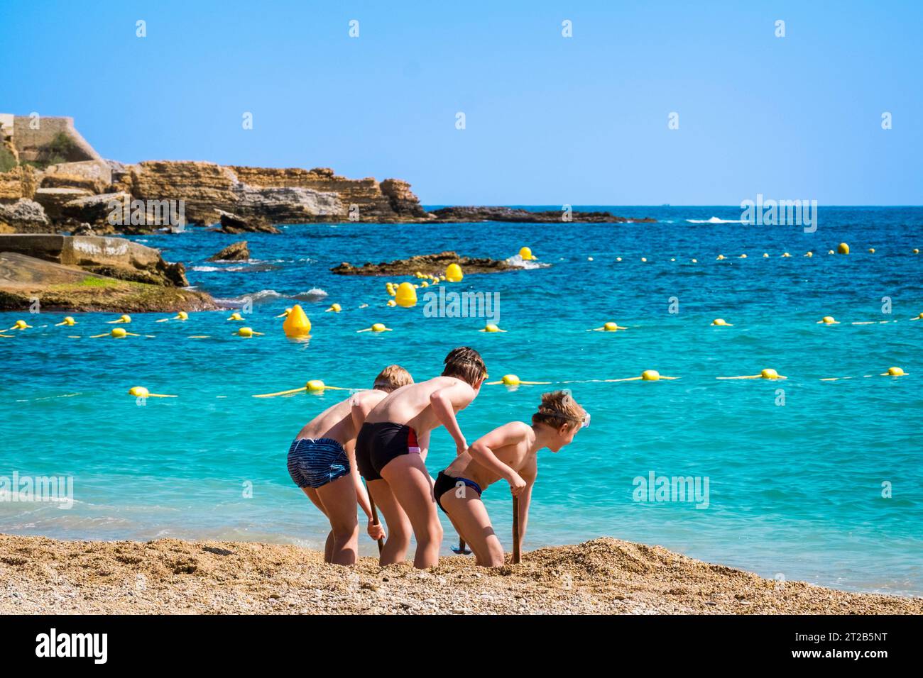 Trois jeunes garçons creusant dans le sable sur la plage de Cassis, dans le sud de la France. Banque D'Images