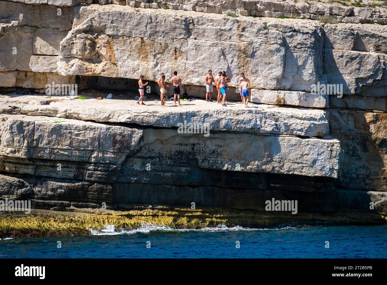 Plusieurs hommes adultes se rassemblent sur une falaise calcaire dans l'une des calanques près de Cassis, dans le sud de la France. Banque D'Images