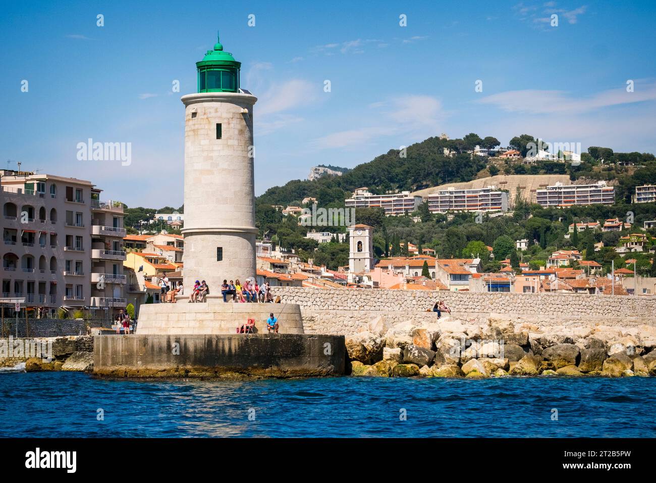 Les gens se détendent au pied du phare de Cassis qui se dresse à l'embouchure du port de Cassis, dans le sud de la France. Banque D'Images