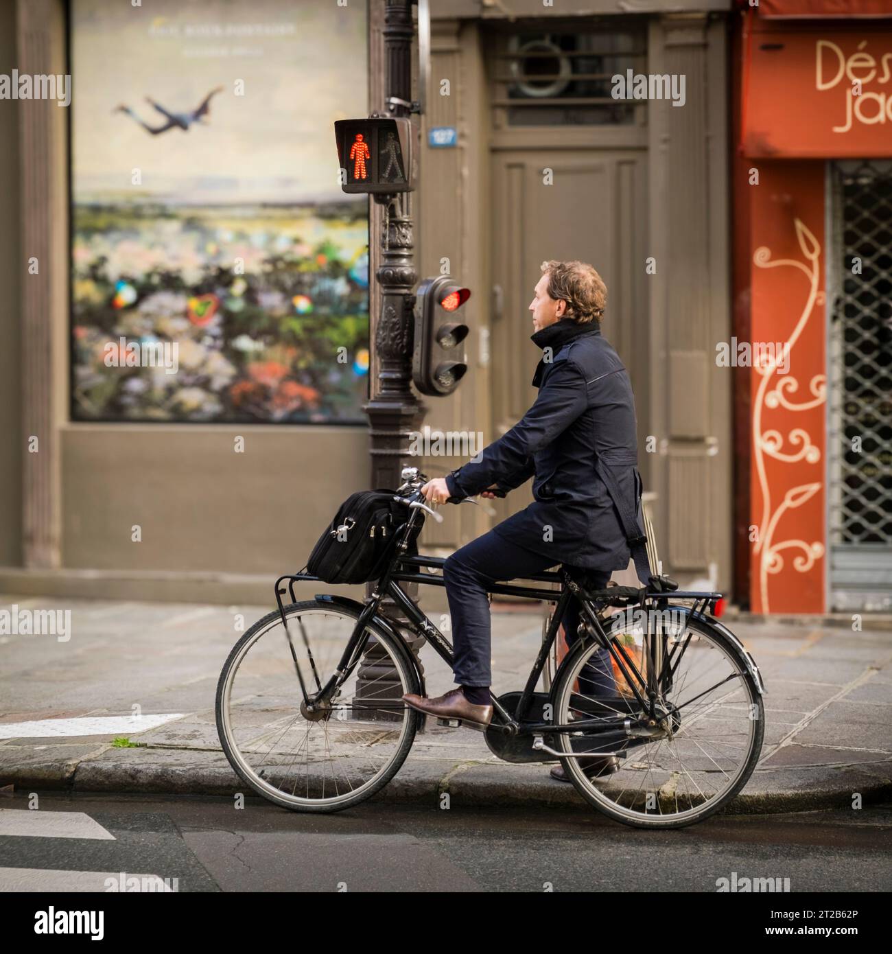 Un homme d’affaires attend un feu de circulation sur son vélo dans le quartier du Marais à Paris, France. Banque D'Images